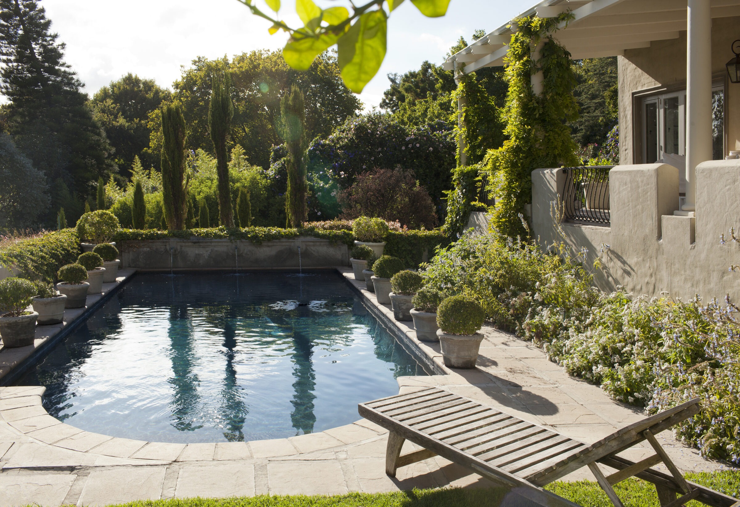 Luxury eco-friendly pool design in a backyard, surrounded by lush greenery in the evening.